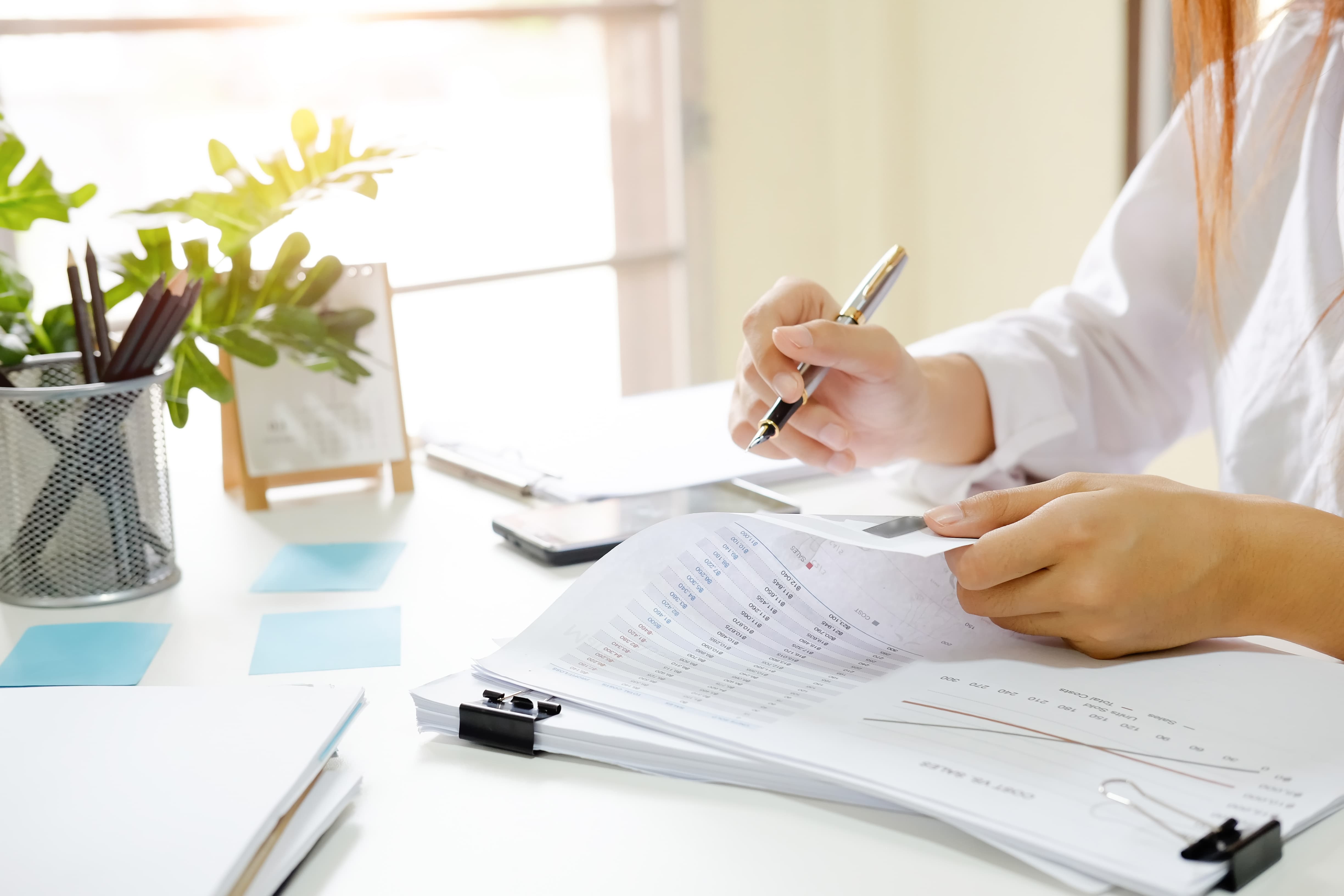 office worker looking over spreadsheets with pen in hand