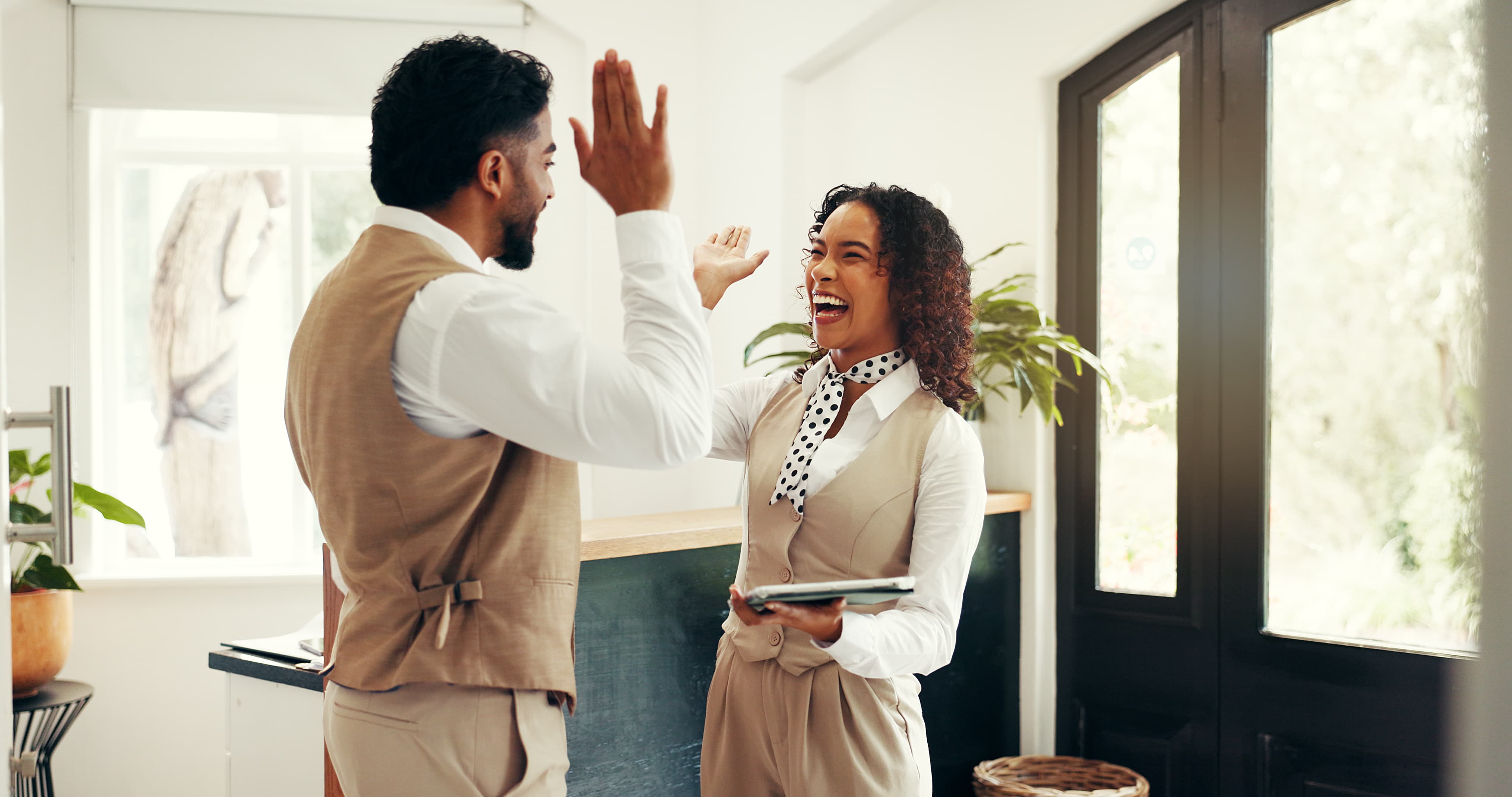 two hotel employees high fiving and smiling
