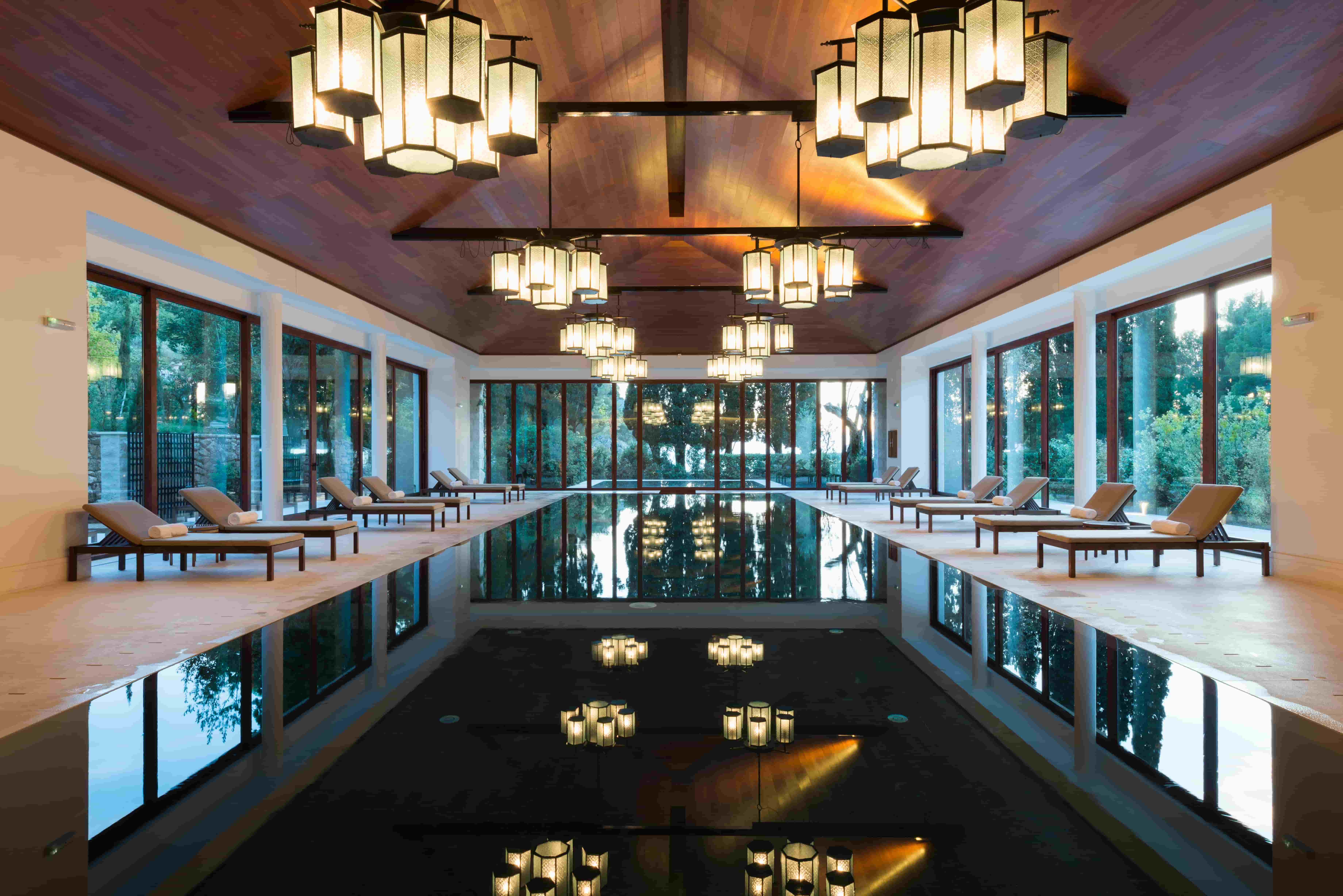 A highly aesthetic luxury spa setting, with pool, dim lighting, and deck chairs