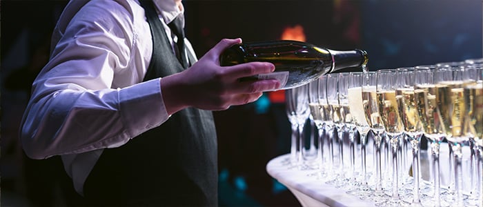 waiter pours champagne into elegant glasses at a stylish bar