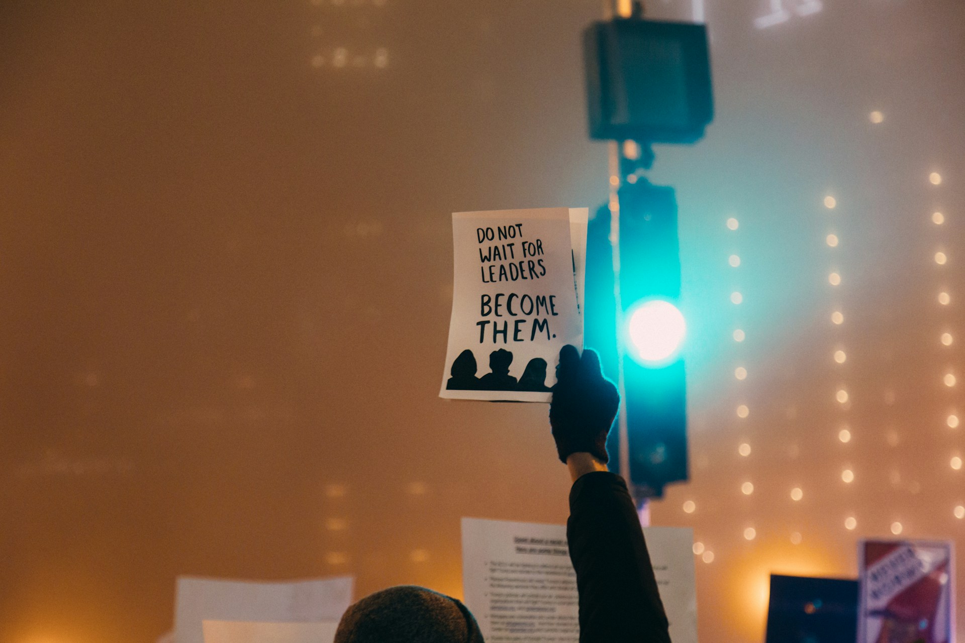 Person holding up a sign that says "don't wait for leaders"