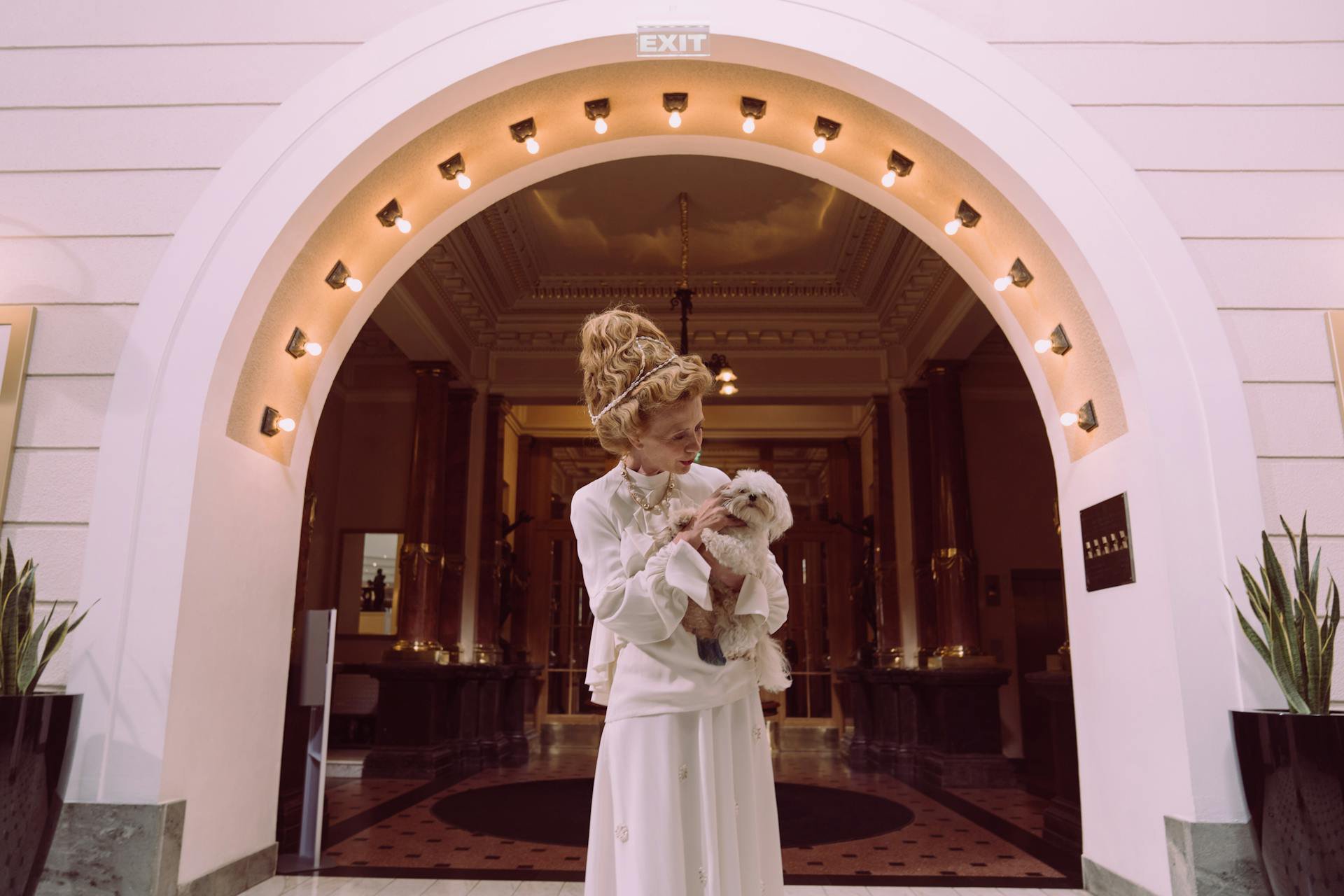 A woman holding a shih tzu puppy at a hotel entrance 