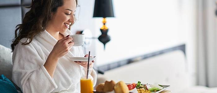 A woman in a bathrobe enjoys breakfast