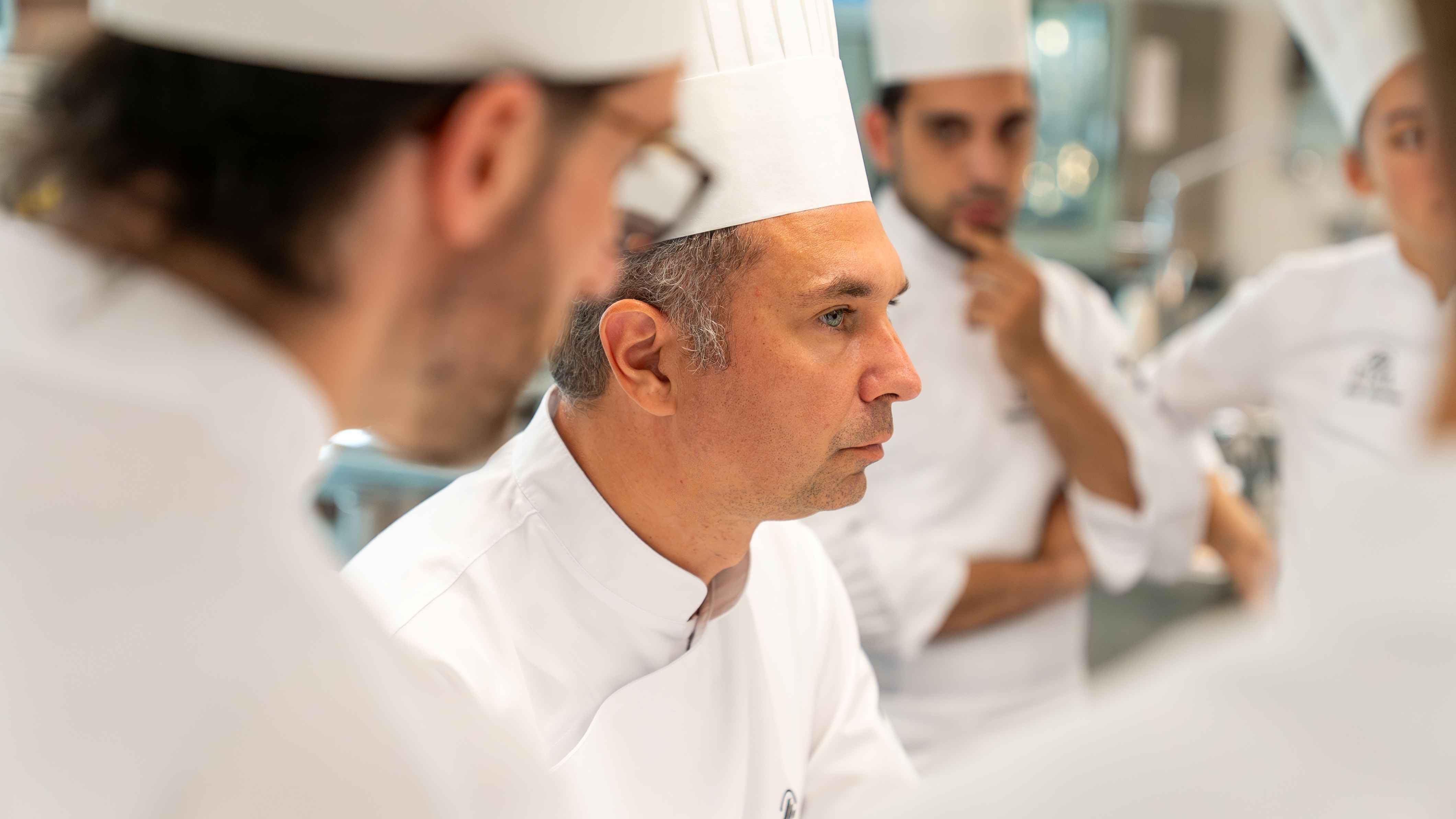 Side profile of a kitchen chef, wearing a chefs hat